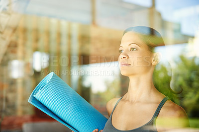 Buy stock photo A poised young woman looking away while holding her yoga mat