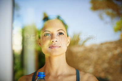 Buy stock photo A fit woman daydreaming behind glass window with copyspace. Athletic female excited for her future, planning goals while sipping on bottled water to replenish electrolytes lost during a workout