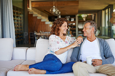 Buy stock photo A happy mature couple enjoying a cup of coffee together on the sofa at home