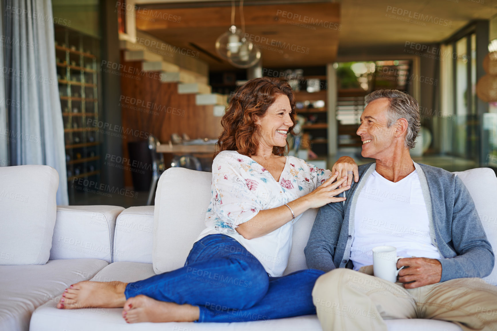 Buy stock photo A happy mature couple enjoying a cup of coffee together on the sofa at home