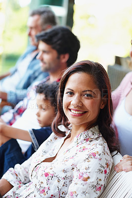 Buy stock photo A smiling young woman looking at the camera while sitting with her family