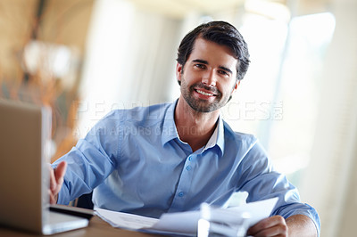 Buy stock photo A handsome young businessman working on his laptop at his desk