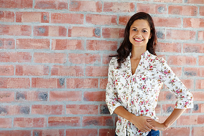 Buy stock photo An attractive young woman standing in front of a brick wall with her hand on her hip