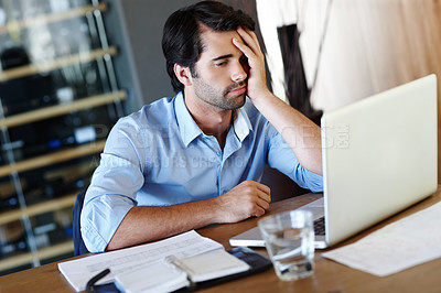 Buy stock photo A frustrated employee sitting at his desk and working on his laptop