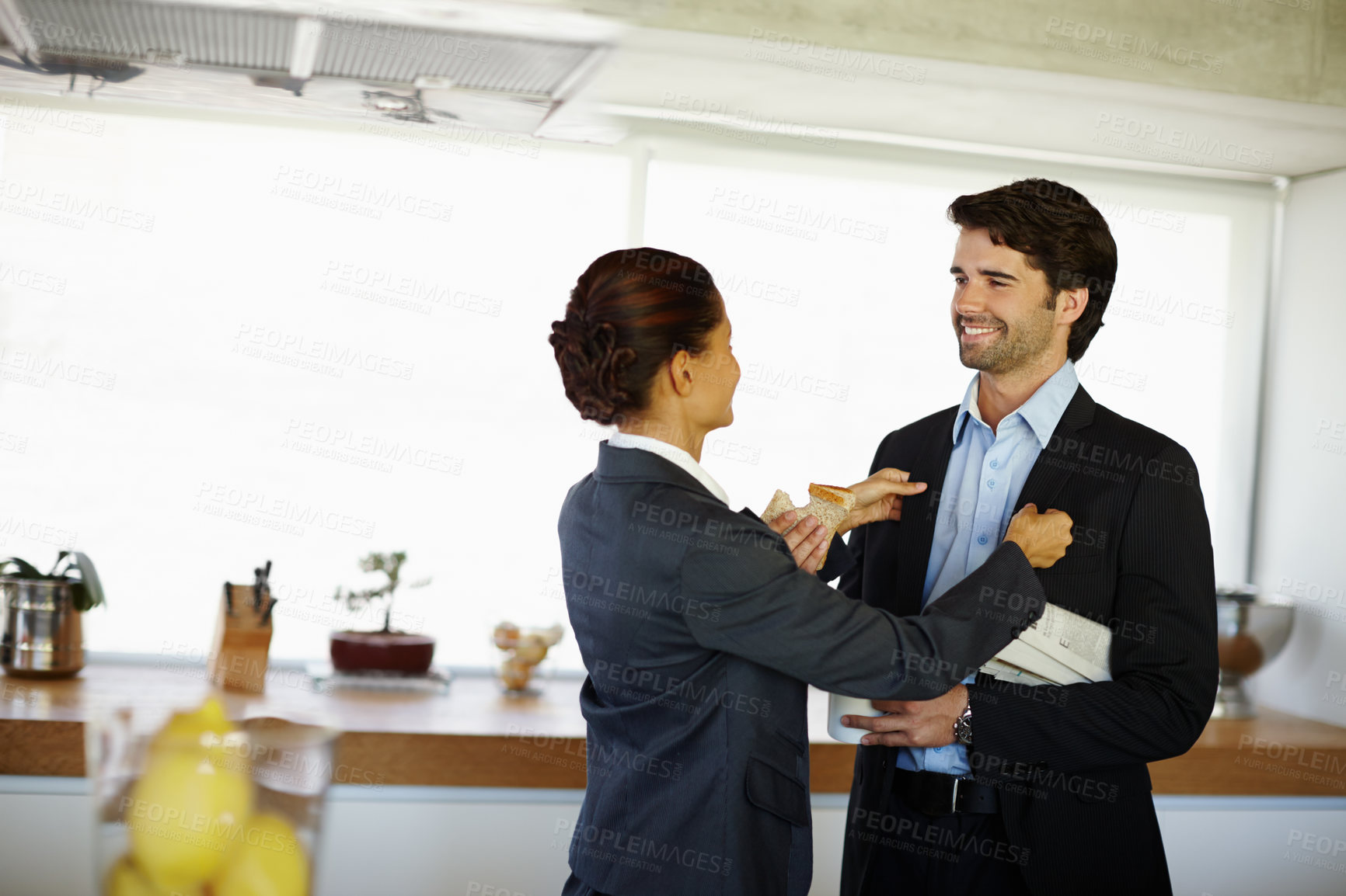 Buy stock photo Attractive woman adjusts her husbands jacket before he leaves for work