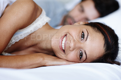 Buy stock photo Smiling young woman lying in bed alongside her boyfriend