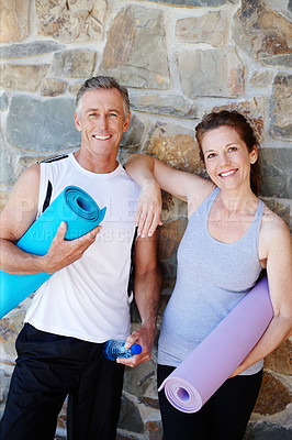 Buy stock photo A mature couple holding their yoga gear outside with broad smiles