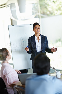 Buy stock photo An attractive young woman giving a business presentation to a group of colleagues
