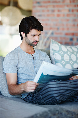 Buy stock photo Shot of a man reading his newspaper in his living room