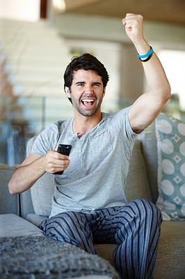 Buy stock photo Portrait of an excited man watching television in his lounge 