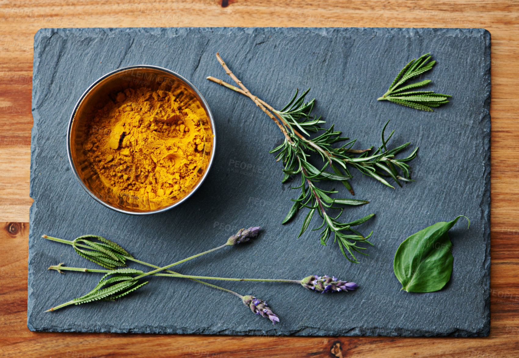 Buy stock photo High angle shot of a bowl of turmeric with herbs beside it