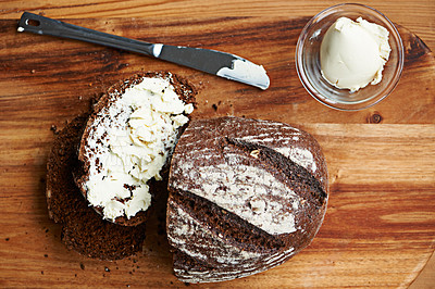 Buy stock photo Sourdough, bread and butter on slice for baking, nutrition and carbs on kitchen table or fibre. Top view, wheat and rye snack on wooden board, grain and organic ingredients for artisan meal in home