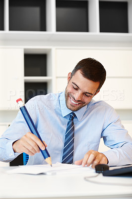 Buy stock photo Office, smile and businessman with big pencil by desk for corporate finance, planning and notes. Happy, man and writing on paper at workplace for investment, budget idea and research of economy