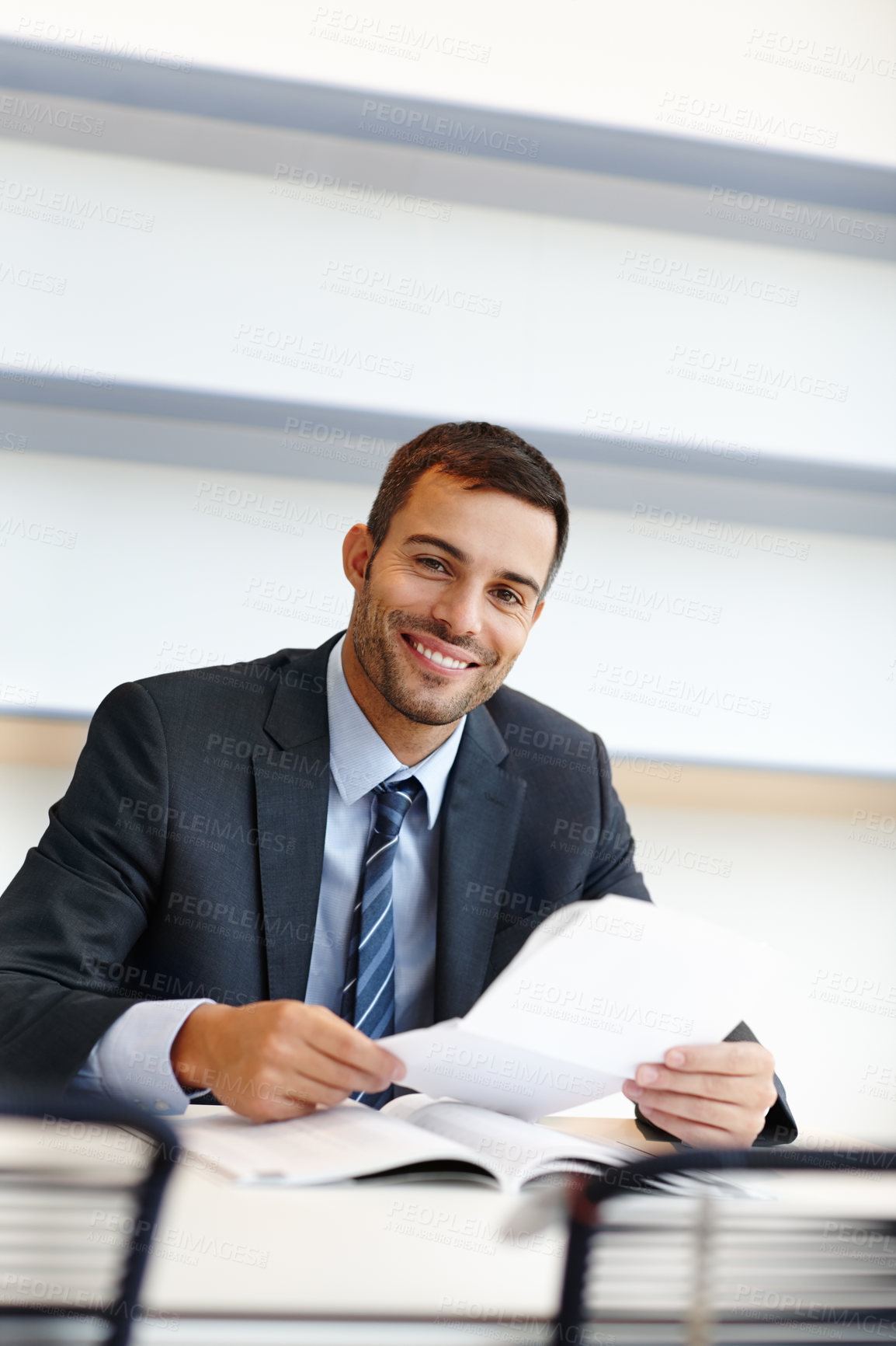 Buy stock photo Portrait of one corporate businessman sitting alone in his office and reading paperwork. Confident and ambitious lawyer and paralegal looking at documents and contracts. Young professional attorney