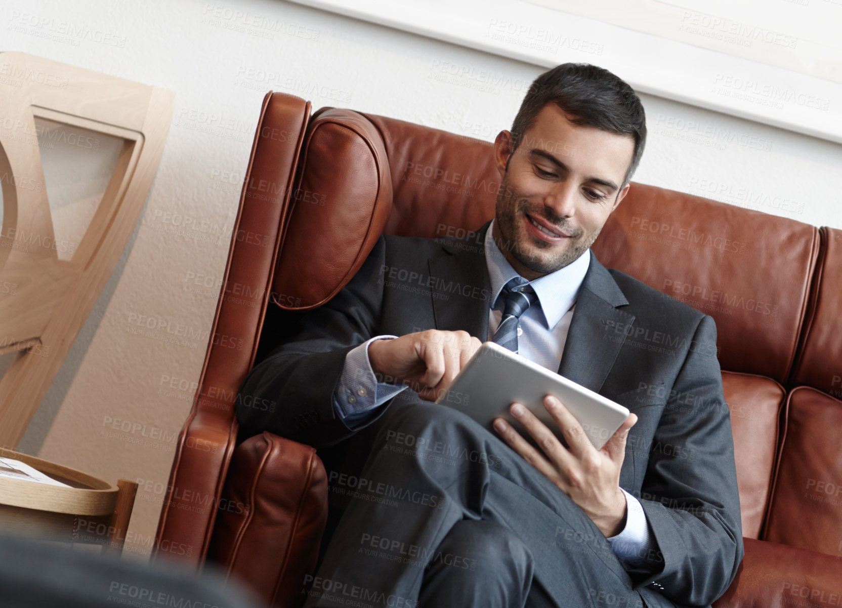 Buy stock photo Reading, tablet and corporate man on couch for online, research and smile in waiting room. Trader, stock market and internet with technology for planning and proposal for business meeting in New York