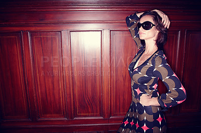 Buy stock photo One fashionable trendy woman wearing sunglasses and a stylish dress while standing against a wooden door or wall inside. Playful model posing while partying. Cool edgy female enjoying a party