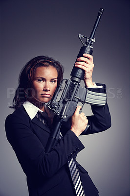 Buy stock photo A young businesswoman wearing a suit and tie holding a rifle