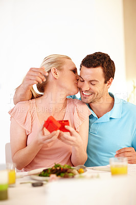 Buy stock photo A beautiful woman giving her boyfriend a kiss as she holds a jewellery box in her hands