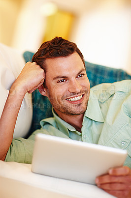 Buy stock photo A handsome man relaxing on the couch with his digital tablet