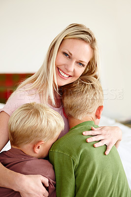 Buy stock photo A mother smiling at the camera while hugging her two sons