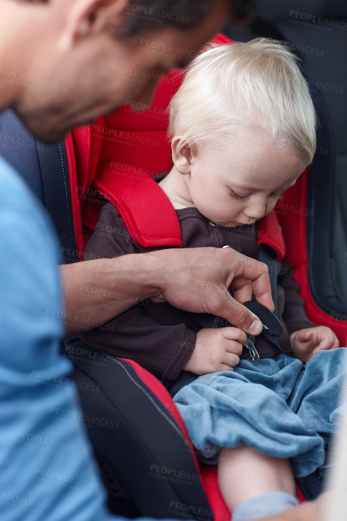 Buy stock photo A father helping his child in a baby seat for the car
