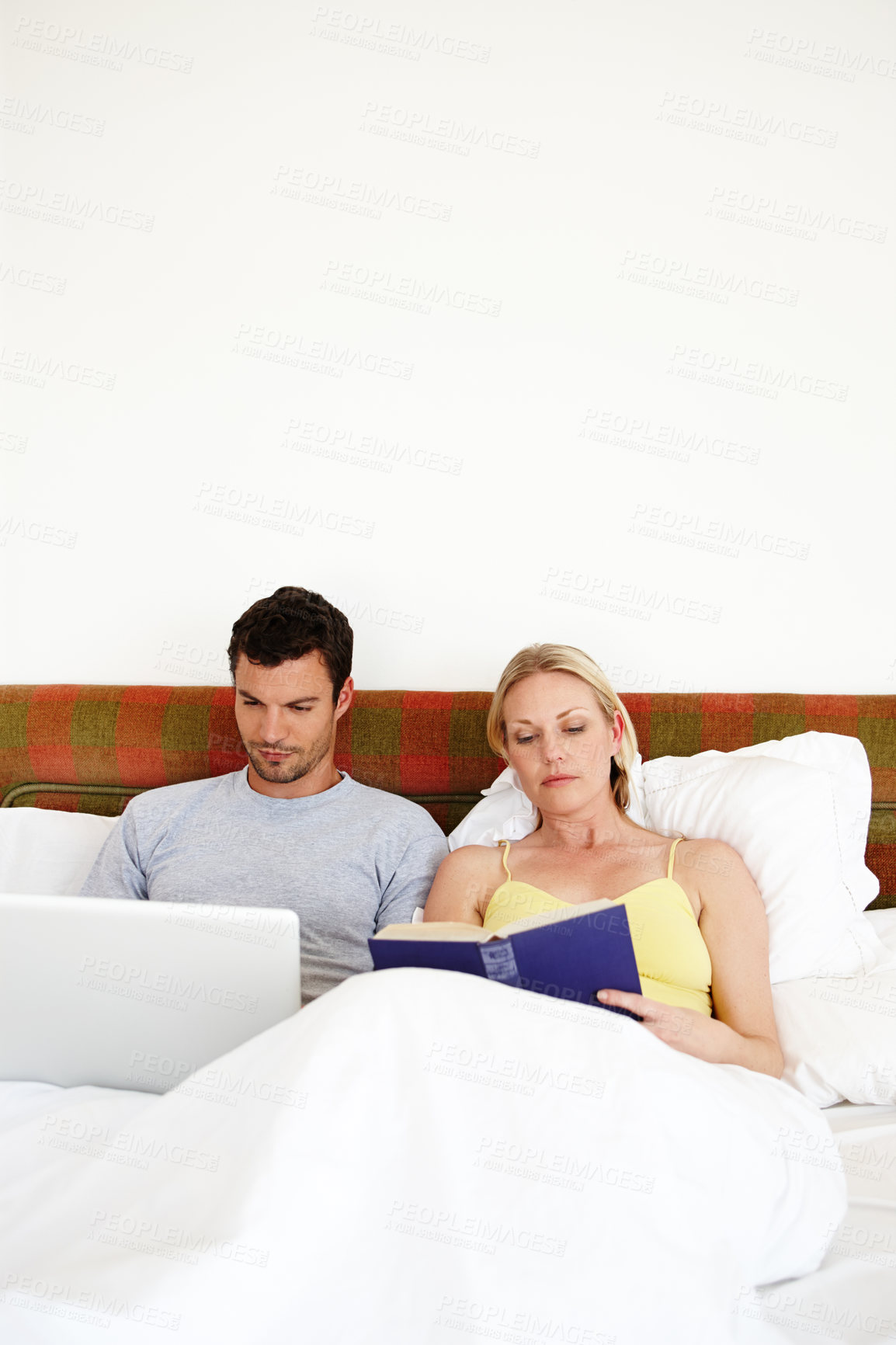 Buy stock photo Couple, bed and book or laptop in home for social media browsing, internet search and reading. People, technology and novel in bedroom for story, watching movie or knowledge with mockup on weekend