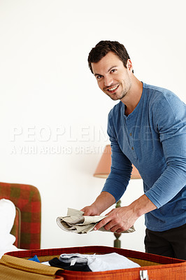 Buy stock photo A young man packing a suitcase on his bed at home