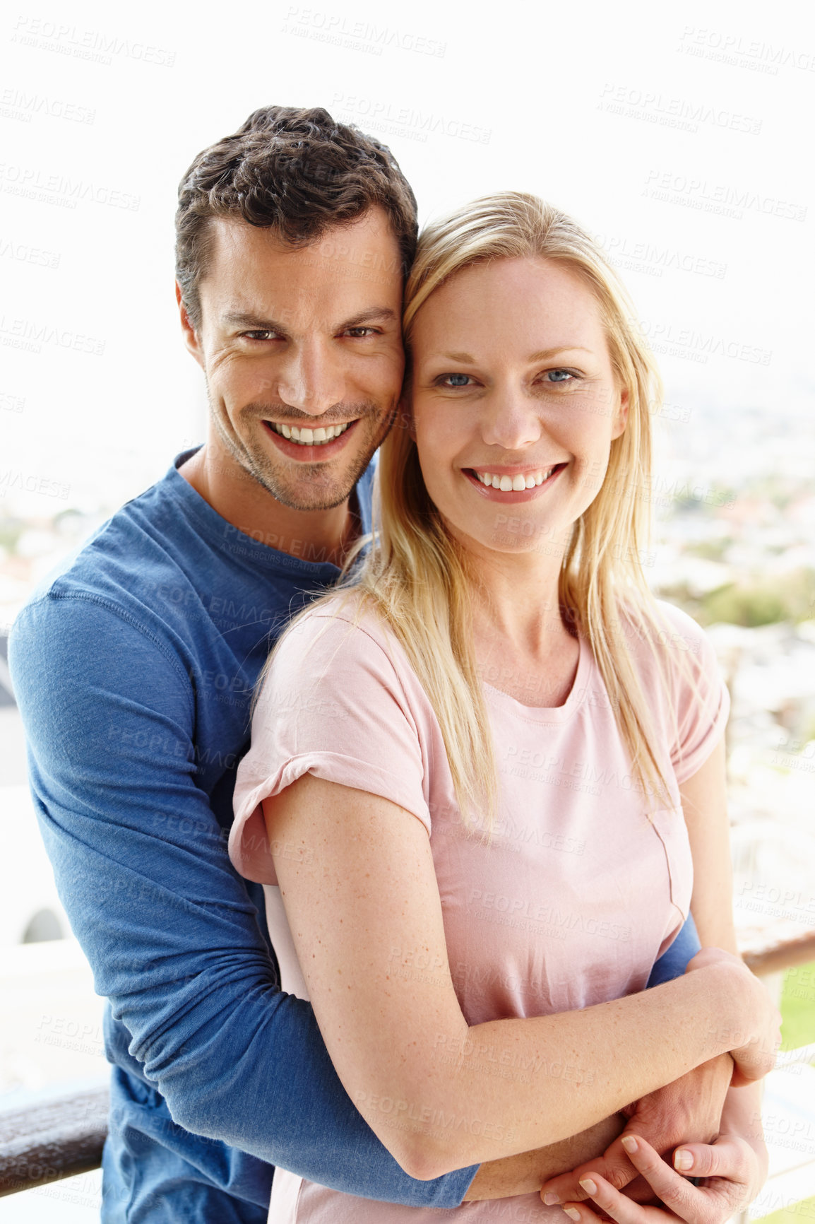 Buy stock photo A happy young couple standing together and smiling