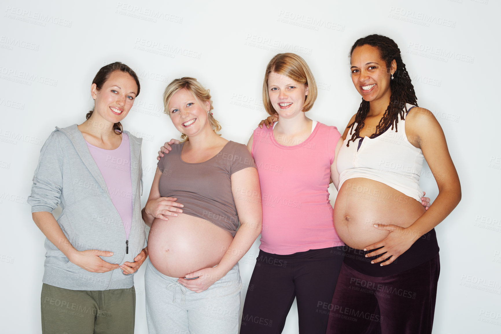 Buy stock photo Pregnant, mother and friends with women in studio against a white background feeling happy with a smile. Pregnancy, health and wellness with positive female parents holding their abdomen together