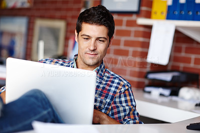 Buy stock photo A handsome young designer working on his laptop in the office