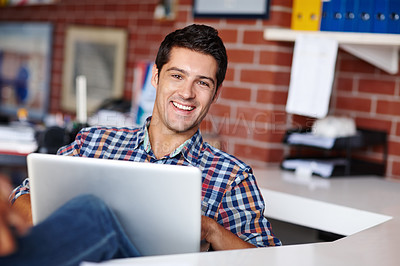 Buy stock photo Portrait of a handsome young designer working on his laptop in the office