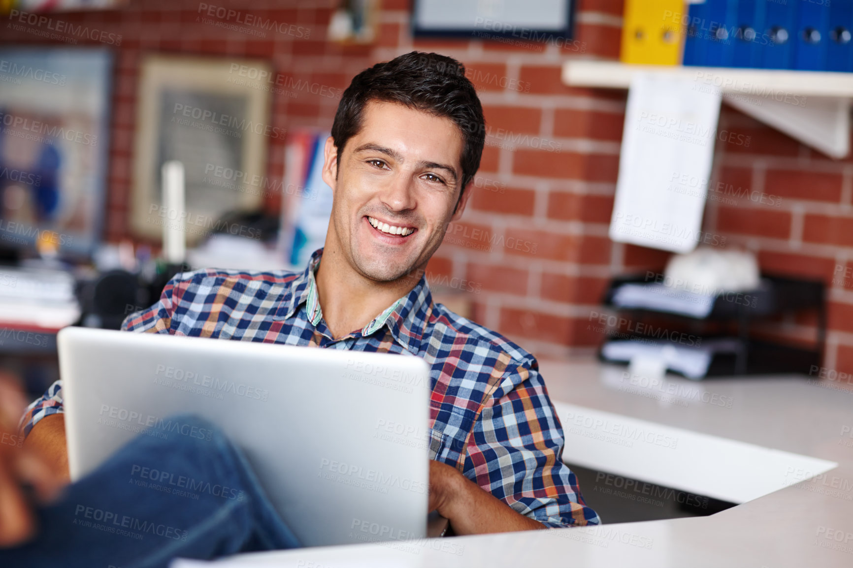 Buy stock photo Portrait of a handsome young designer working on his laptop in the office