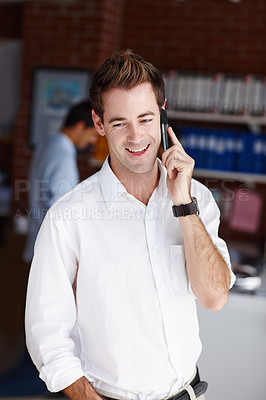 Buy stock photo A handsome young businessman taking a call from a client