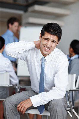 Buy stock photo A young businessman frowning as he rubs his sore neck