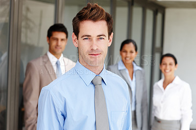 Buy stock photo A young business leader standing in front of his team confidently