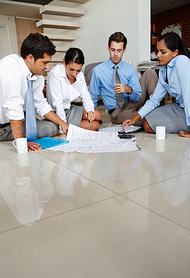 Buy stock photo Four business colleagues going over the floor plan for their new office space