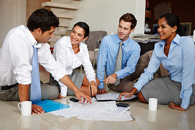 Buy stock photo Four business colleagues going over the floor plan for their new office space
