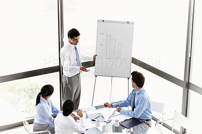 Buy stock photo A young businessman presenting to his colleagues in the boardroom