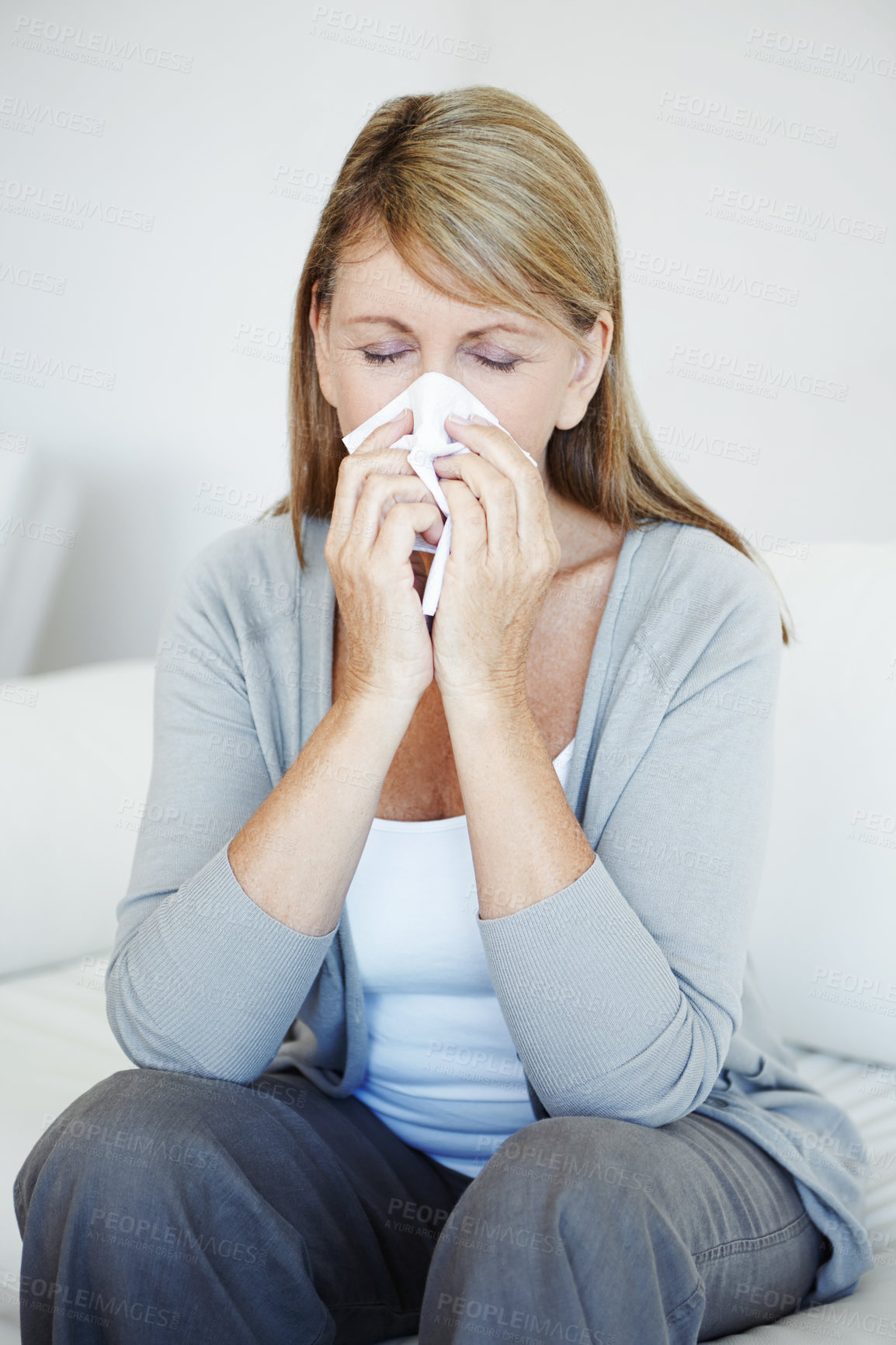 Buy stock photo Woman, sick and blowing nose with tissue for virus, allergy  or cold flu on sofa at home. Mature female person with hayfever, sinus or covid in sneeze, respiratory disease or viral infection at house