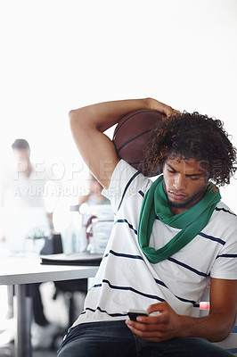 Buy stock photo A young man playing with a basketball while sitting in the office
