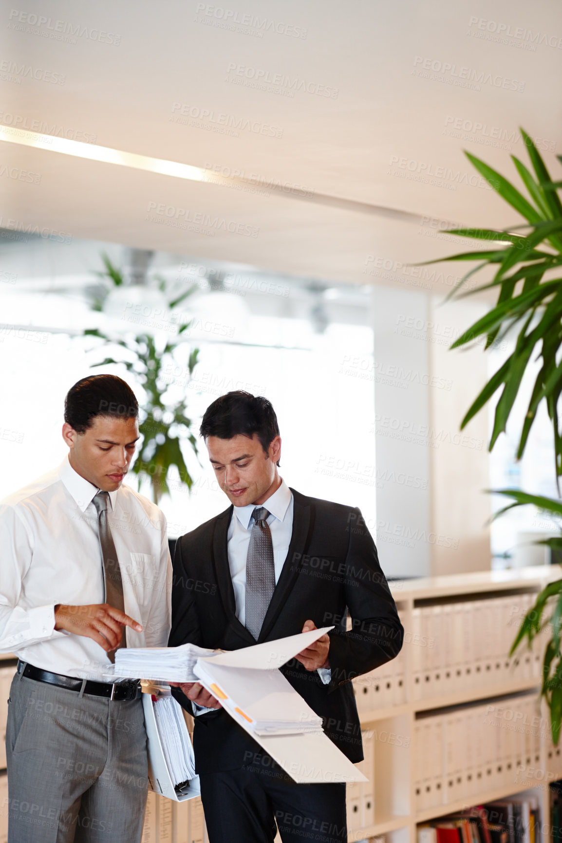 Buy stock photo Two suit-clad businessmen working together while in the office