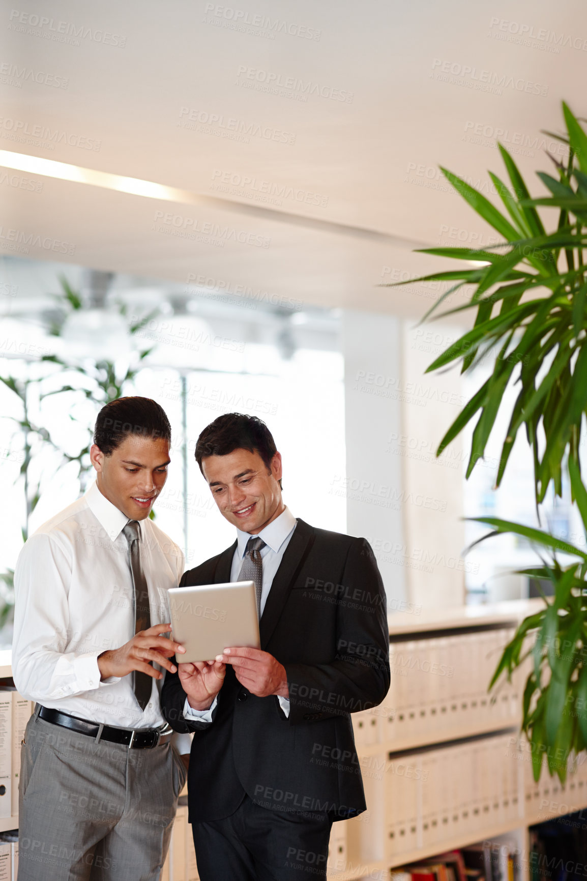 Buy stock photo Two suit-clad businessmen working together while in the office