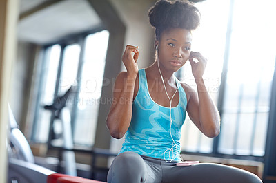 Buy stock photo Woman, earphones and sitting in gym for exercise with fit body, endurance and healthy workout. Training, streaming music and face of athlete in facility for wellness, listening and rowing machine