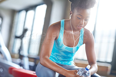 Buy stock photo Fitness, earphone and black woman in gym, music and streaming audio in sportswear. Workout, sports and bottle for female athlete person, podcast or motivation in wellness facility for cardio exercise