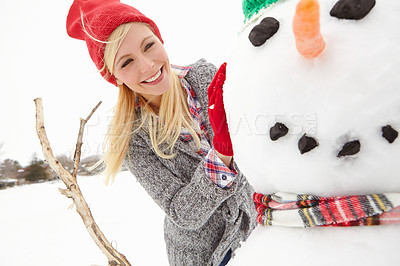 Buy stock photo Winter, christmas and snowman with a woman outdoor in nature during a holiday or vacation as a tourist. Snow, cold weather and smile with a happy young female outside for fun in the festive season
