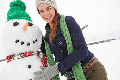 Buy stock photo Cropped shot of a beautiful young woman standing beside a snowman