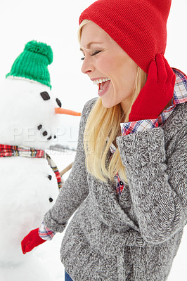 Buy stock photo Cropped shot of a beautiful young woman standing infront of a snowman