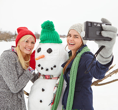 Buy stock photo Selfie, snowman and winter with woman friends taking a photograph outdoor together in the snow. Happy, smile and photography with a young female and friend posing for a picture in the cold weather