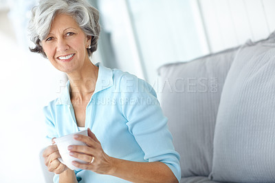 Buy stock photo Portrait of a happy senior woman sitting at home with a warm cup of coffee