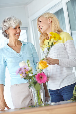 Buy stock photo Flowers, mom and daughter in home to relax together with smile, love and wellness for affection. Mothers day, mature and happy woman bonding in lounge with family, parent and gift present in Germany
